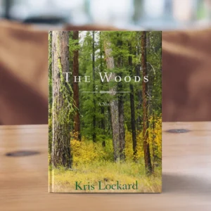 The Woods A Novel by Kris Lockard book standing on a table with a forest cover photo behind title text